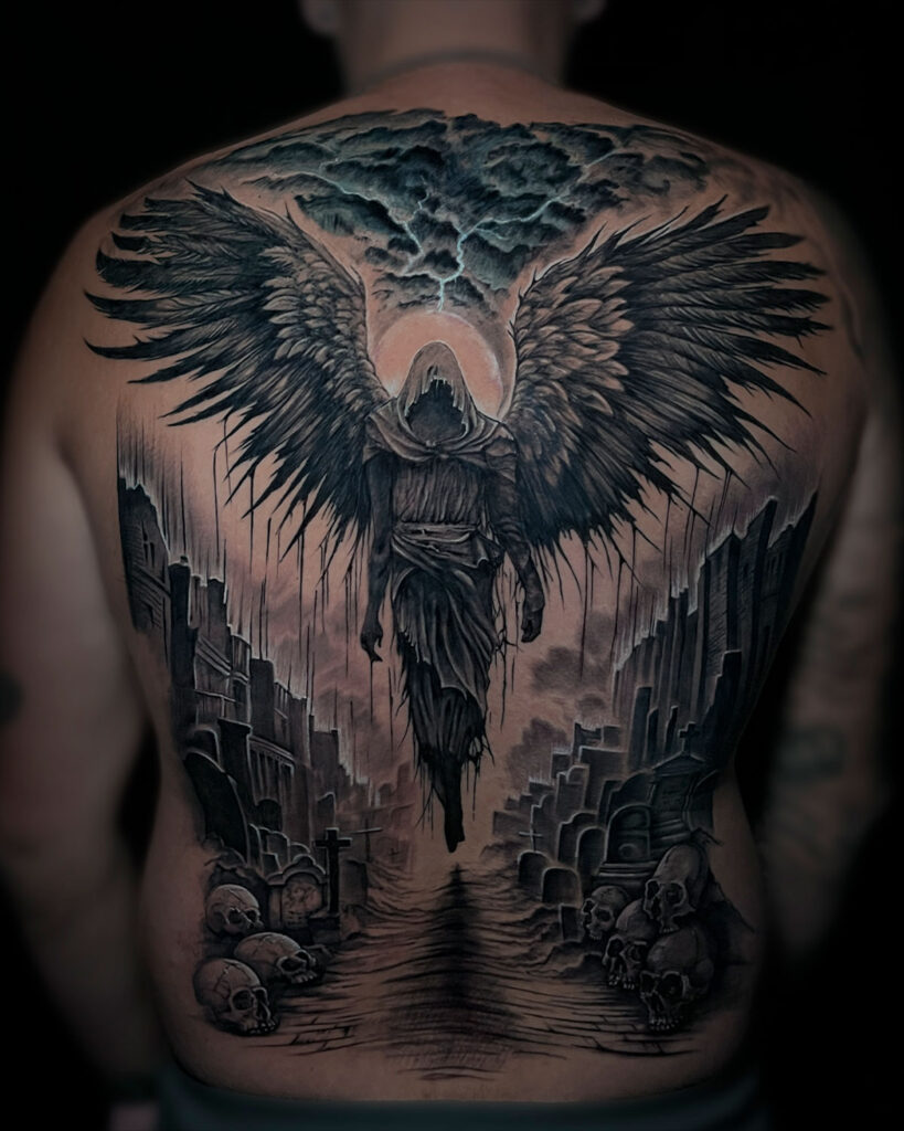 Tatuaje de un ángel oscuro, en medio de una ciudad destruida con tumbas y calaveras, cubriendo la espalda completa, realizado por kaorukel