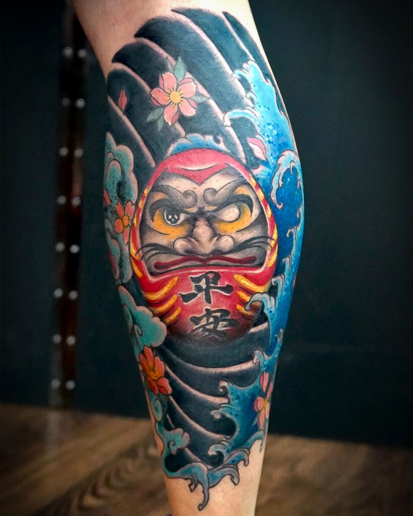 Tatuaje de daruma con olas, sakura y fondo estilo japonés, tatuado por kaorukel