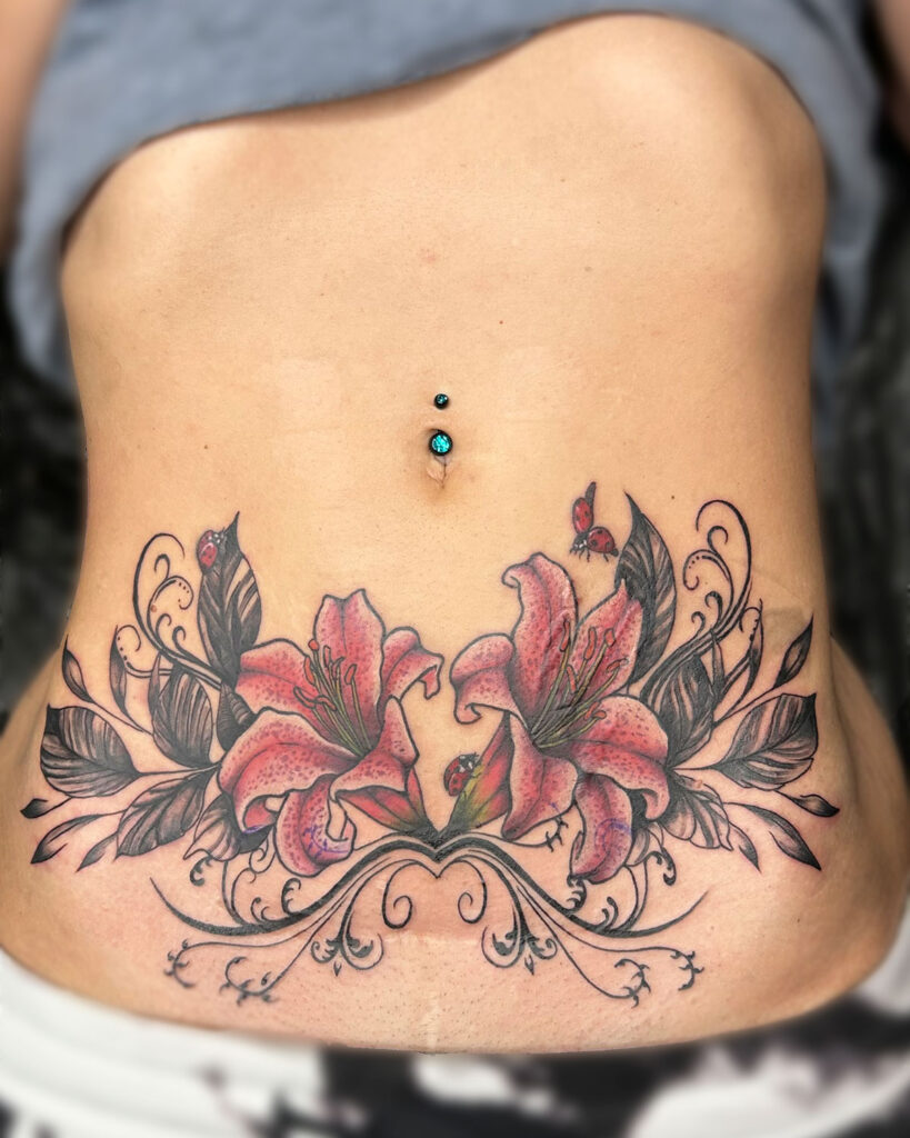 Tatuaje de dos lirios a color, con hojas y mariquitas, en la zona del abdomen, tatuado por kaorukel