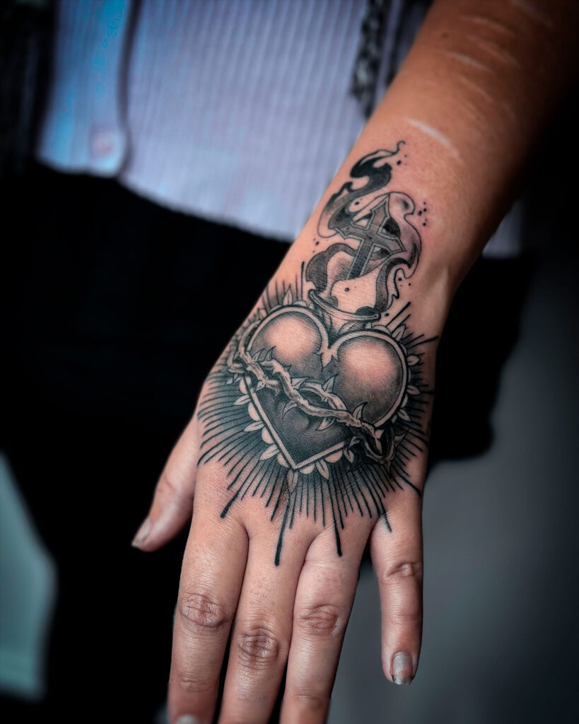 Tatuaje de un sagrado corazón de Jesús, con espinas, realizado en la mano, en blanco y negro, tatuado por kaorukel