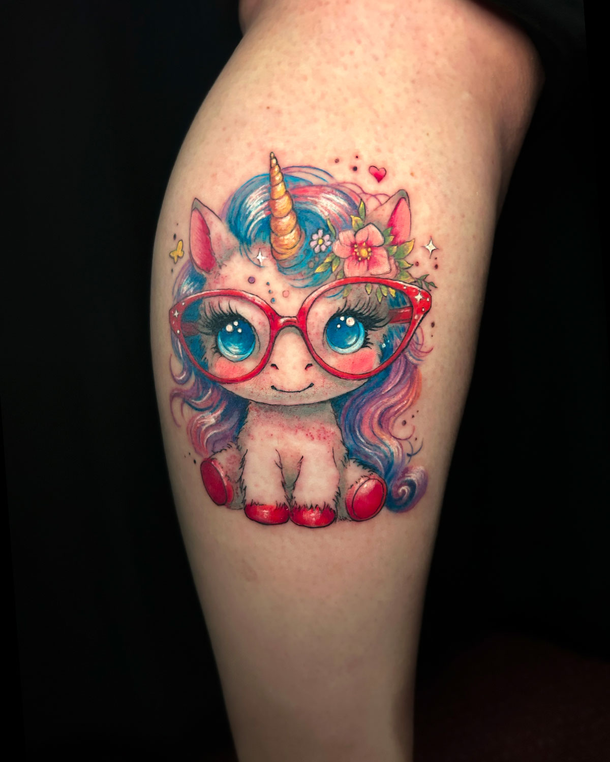 Tatuaje de un unicornio con gafas, estilo kawaii, a todo color, tatuado por kaorukel